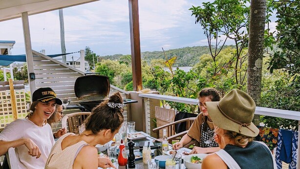 Un groupe de personnes est assis à une table en plein air, profitant d’un paysage vallonné.