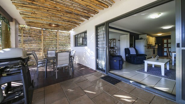 A covered patio area with a grill, seating, and a view into the living room. - Seychelles Ground Level 2 Bedroom air-con self-contained apartment,  River views (Wooli)