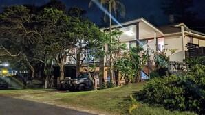 A two-story house with a balcony, surrounded by lush greenery and a parked car. - Seychelles Ground Level 2 Bedroom air-con self-contained apartment,  River views (Wooli)