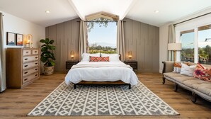 Een slaapkamer met een groot bed, een bank, een kaptafel en een potplant.