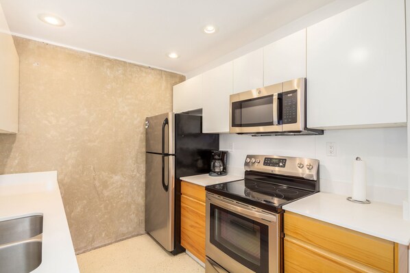 Fully equipped kitchen with stainless steel appliances, a sink, and a coffee maker.