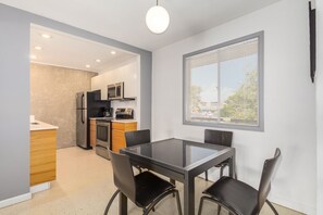 A modern kitchen with a dining area, featuring a glass table and chairs, a built-in oven, and a microwave. - One Bedroom Condo Close to All the Action (Scottsdale)