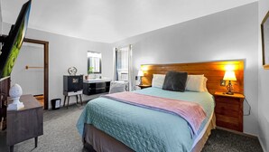 A bedroom with a bed, bedside tables, a dresser, a mirror, and a window.