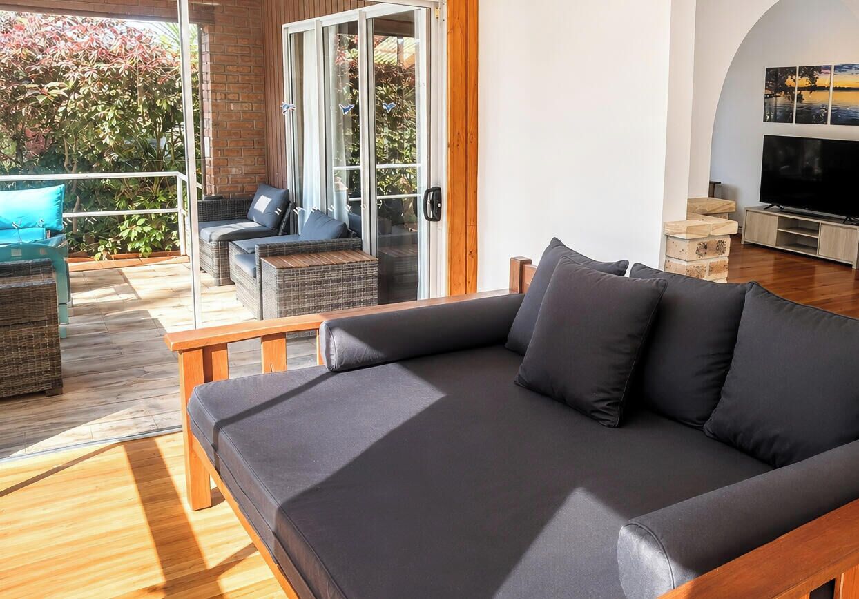 A modern living room with a sofa, a television, and a sliding glass door leading to an outdoor area.