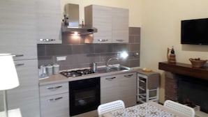 A compact kitchen with modern appliances, a built-in oven, and a dining area with a table and chairs. - 500 mt from Porta Rudiae (Lecce)