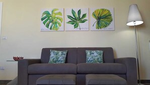 A living room with a grey sofa, two matching cushions, and three framed botanical prints on the wall. - 500 mt from Porta Rudiae (Lecce)