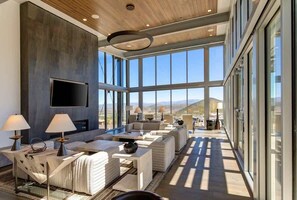 A spacious living area with a large TV, comfortable seating, and a view of the mountains.