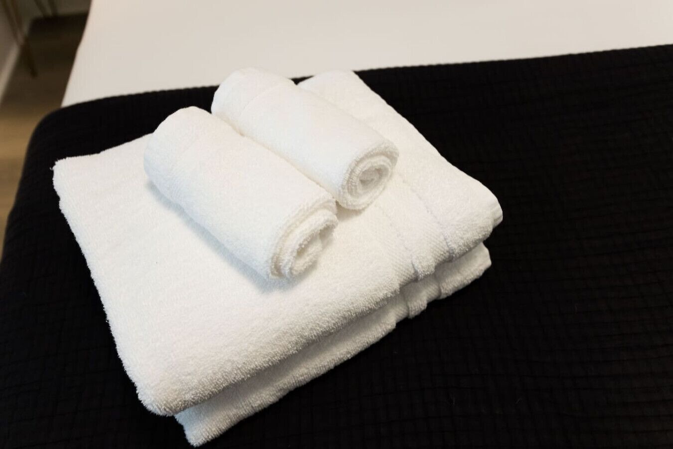 Two white towels folded on a black surface.
