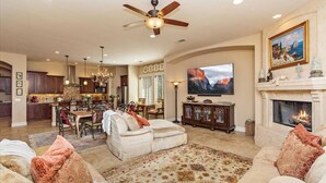 A spacious living room with a fireplace, a dining area, and a kitchen.