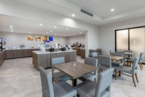 Un moderno vestíbulo de hotel con una zona de bar central, áreas de estar y un diseño limpio y contemporáneo.