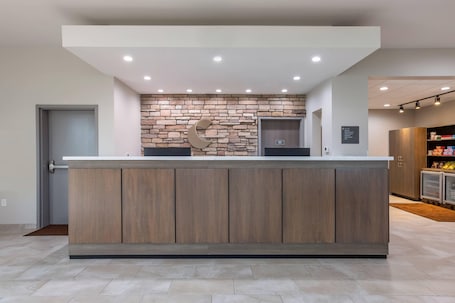 A reception area with a stone wall, a wooden reception desk, and a modern elevator.