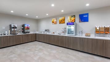 A modern kitchen area with a coffee machine, a refrigerator, and a bread display.