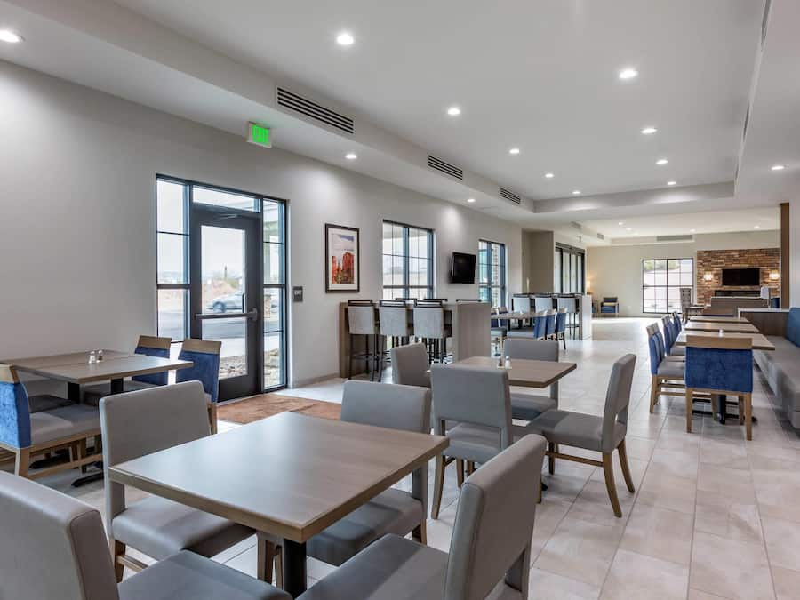 A modern dining area with multiple tables and chairs, a fireplace, and a television mounted on the wall.