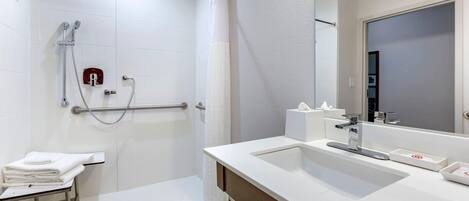 A modern bathroom with a walk-in shower, a sink with a mirror, and a towel rack.