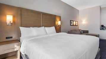 A hotel room with a large bed, bedside tables, a desk, and wall-mounted lamps.