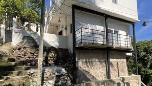 A two-story building with a balcony, stone steps, and a clear blue sky.