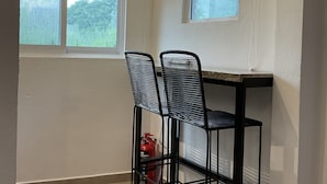 A small room with a table and two chairs, a window, and a ceiling light.