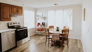 A kitchen with wooden cabinets, a stainless steel oven, and a dining table with chairs. - The Franklin Green House in the heart of Berne, Indiana (Berne)