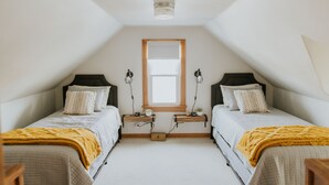 A small, well-lit room with two beds, a window, and a wooden shelf. - The Franklin Green House in the heart of Berne, Indiana (Berne)