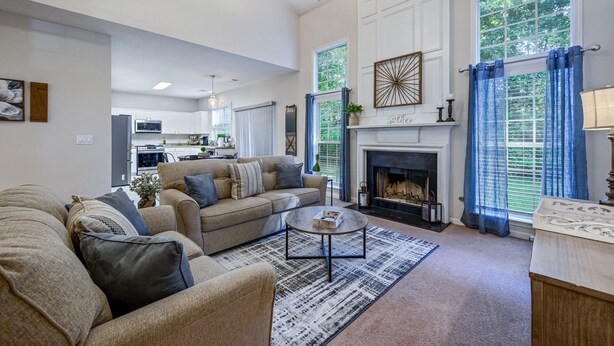 A spacious living room with a fireplace, a dining area, and a kitchen in the background. - Pet-Friendly 3BR Home with Porch & Grill (Woodstock)