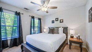 A bedroom with a bed, a nightstand, a lamp, a ceiling fan, and a window with curtains. - Pet-Friendly 3BR Home with Porch & Grill (Woodstock)