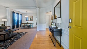A living room with a dining area, a yellow door, and a hallway leading to a bedroom. - Pet-Friendly 3BR Home with Porch & Grill (Woodstock)