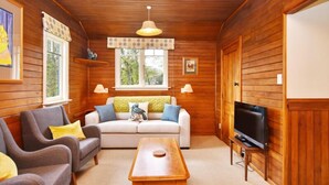 Una sala de estar acogedora con paredes de madera, un sofá, una mesita de centro y un televisor.