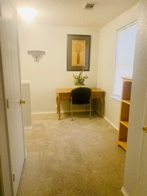 Una habitación con escritorio, silla y un cuadro en la pared.