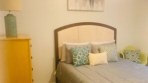 Une chambre à coucher avec un lit, une table de chevet, une lampe et un tableau au mur.