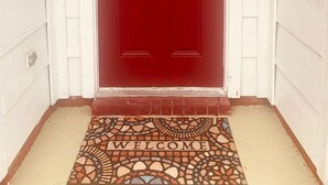 Une porte rouge avec un paillasson devant.