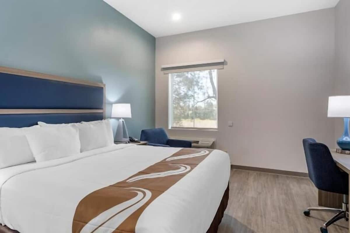 Ein Hotelzimmer mit einem großen Bett, einem Schreibtisch, einem Sessel, einem Fenster und einer Lampe.