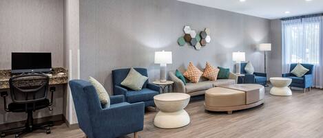 A modern living room with a flat-screen TV, blue armchairs, a sofa, and a coffee table.