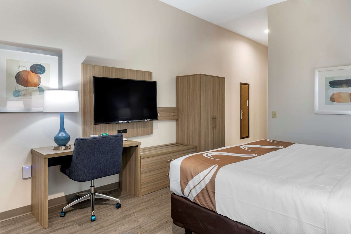 Ein Hotelzimmer mit Bett, Schreibtisch, Stuhl, Fernseher und Kleiderschrank.