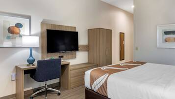 A hotel room with a bed, a desk with a chair, a television, and a wardrobe.