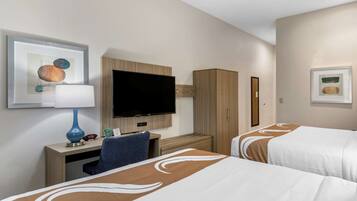 A hotel room with two beds, a desk with a TV, a chair, and artwork on the walls.
