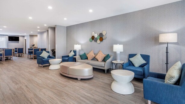 A modern hotel lobby with blue sofas, a round coffee table, and a wall-mounted hexagonal light fixture. - Quality Inn Lebanon - Nashville Area (Lebanon)