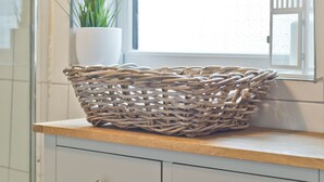A wicker basket on a wooden countertop above a white cabinet with drawers. - Malleus House (Barrow-in-Furness)