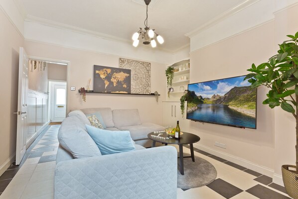 A living room with a sofa, a TV, a world map, and a plant. - Malleus House (Barrow-in-Furness)