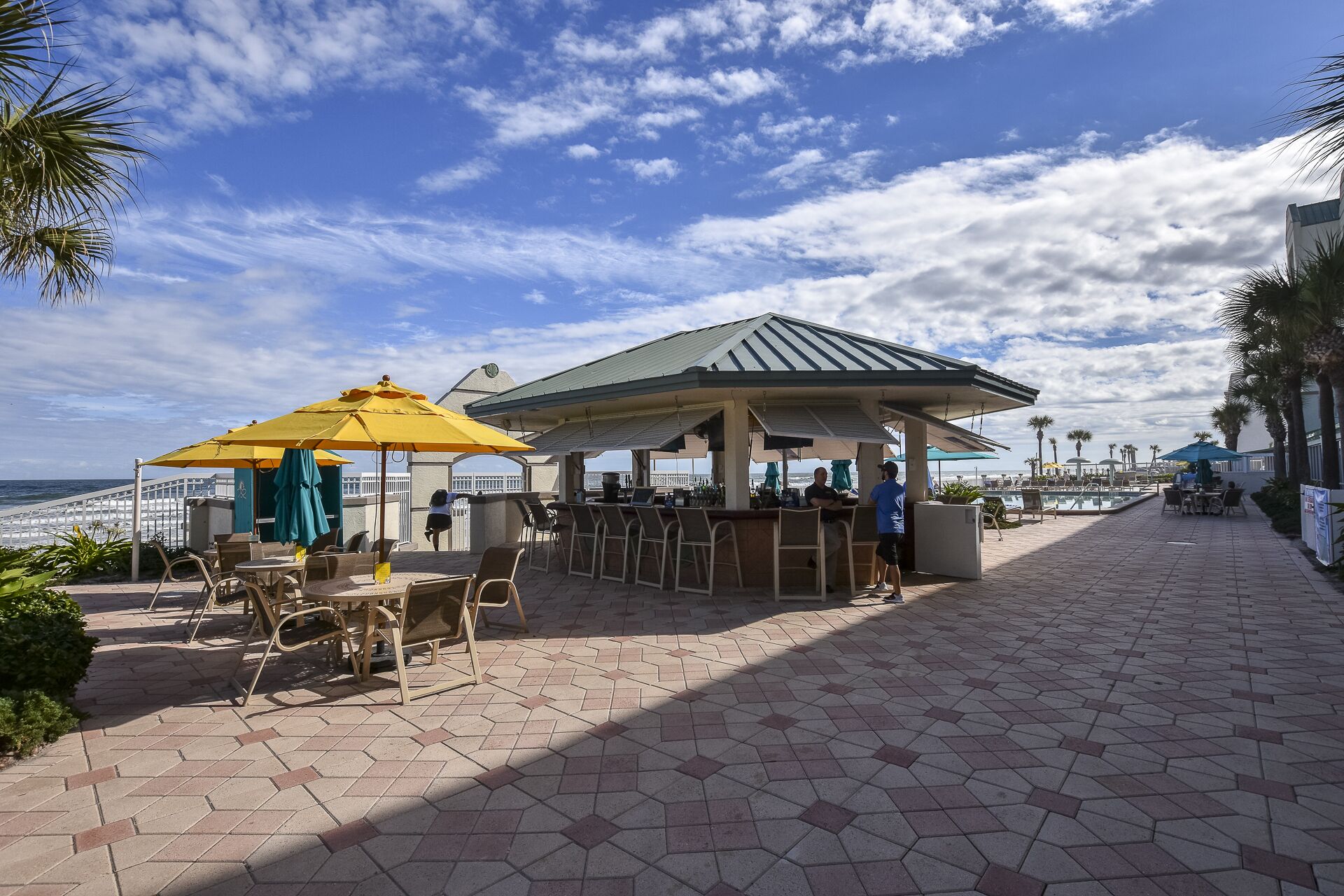 Une terrasse au bord de la plage, avec des sièges en plein air, un espace bar et une vue sur l’océan.