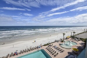 A beach resort with a swimming pool, lounge chairs, and a view of the ocean. - Ocean Views clean room with small balcony no amenities until end of Nov (Daytona Beach)