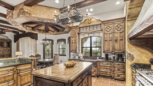 A spacious kitchen with wooden cabinetry, a large island, and a hanging chandelier. - The Spanish Castle | West facing pool, SPA and views of Jack Nicklaus Golf Course (Kissimmee)
