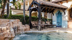 A pool area with a waterfall, outdoor furniture, and a covered seating area. - The Spanish Castle | West facing pool, SPA and views of Jack Nicklaus Golf Course (Kissimmee)