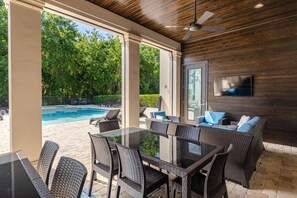 Relax and socialize in this inviting outdoor space with a pool, comfortable seating, and a flat-screen TV.