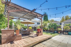 A wooden deck with outdoor furniture, string lights, and potted plants.