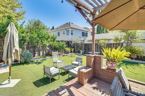 Un jardin avec une terrasse en bois, du mobilier d’extérieur et une pergola.