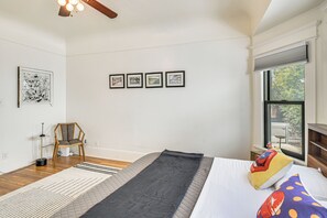 Une chambre à coucher avec un lit, une chaise, un tapis et trois tableaux encadrés accrochés au mur.