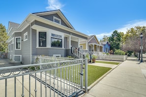 A residential building with a front porch, a gated entrance, and a well-maintained lawn.