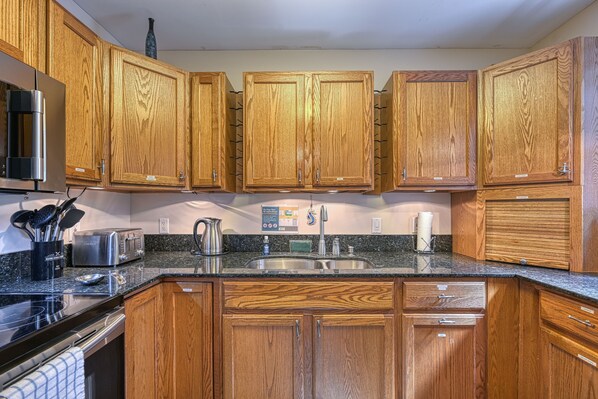 Enjoy cooking in this well-equipped kitchen with a granite countertop, wood cabinetry, and stainless steel appliances.