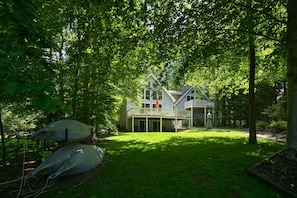 Stunning two-story house with a spacious balcony and traditional pitched roof, set amidst lush greenery and a beautifully manicured lawn.