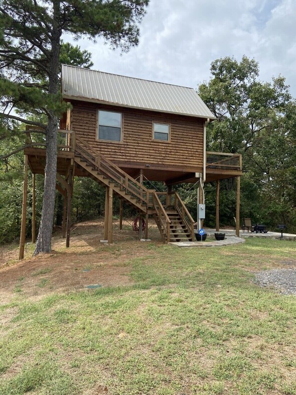 A wooden cabin with a metal roof, a staircase, and a deck.